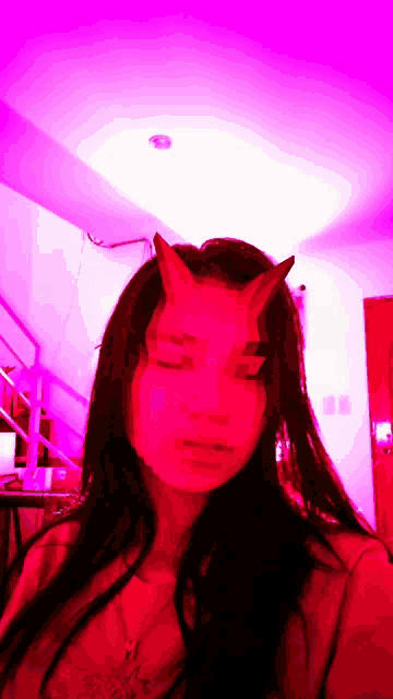 a woman wearing a red mask with horns on her face .