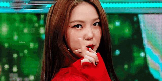 a woman wearing a red sweater holds her hand to her face
