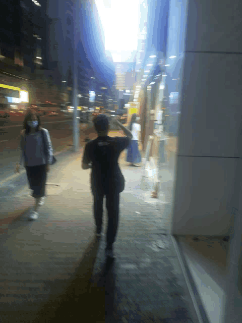a man wearing a black shirt that says ' i love you ' on the back is walking down a sidewalk