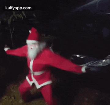 a man in a santa claus costume is dancing in front of a car .