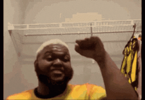 a man wearing a yellow shirt is raising his fist in the air