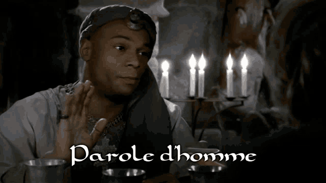 a man sitting at a table with candles and the words parole dhomme on the bottom right