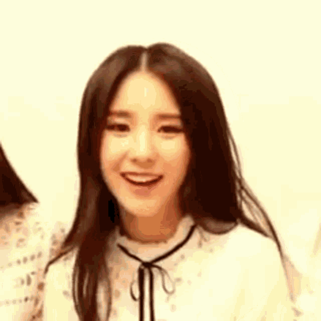 a close up of a woman 's face with long hair wearing a white shirt and smiling .