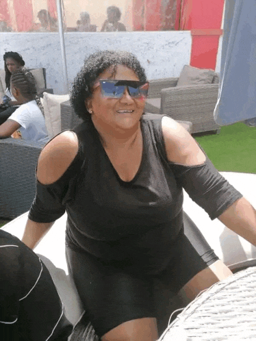 a woman wearing sunglasses and a black shirt is sitting on a couch