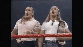 two wrestlers are standing in a wrestling ring .