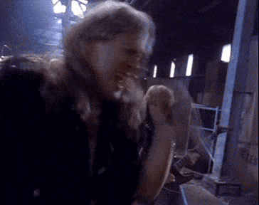 a woman with long hair is standing in a dark room and laughing .