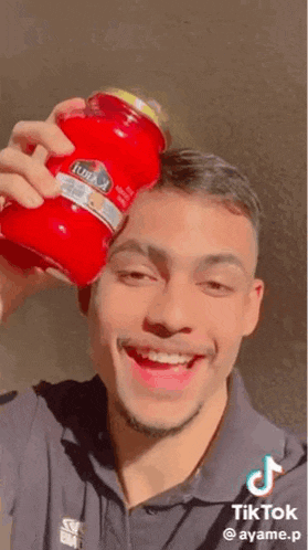a man is smiling while holding a jar of tomato sauce .