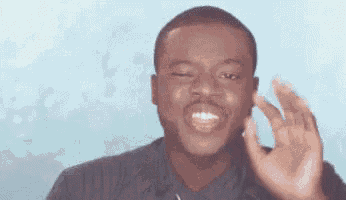 a man in a black shirt is smiling and making an ok sign with his hand .