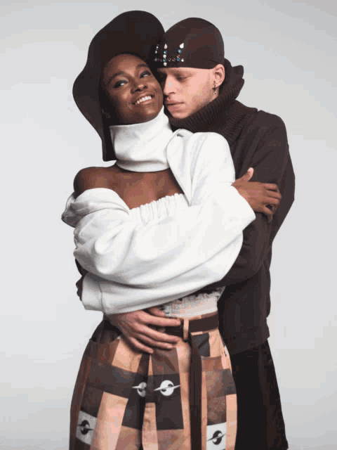 a man is hugging a woman who is wearing a white sweater