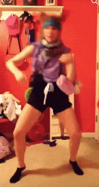 a woman is dancing in a room with a red wall