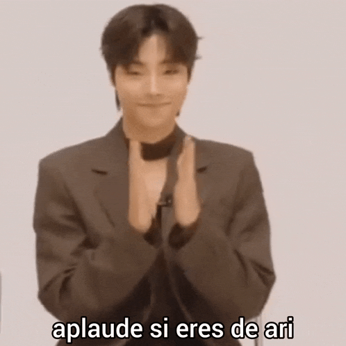 a man in a suit is clapping his hands and says aplaude si eres de ari