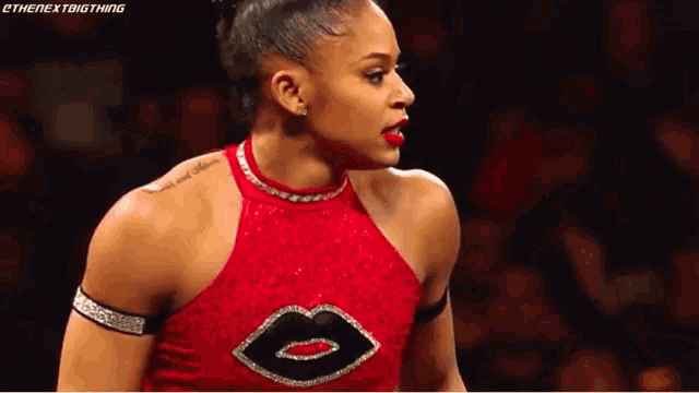 a woman in a red top with a black lip on it is standing on a stage .