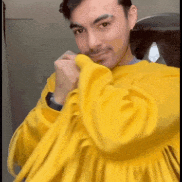 a man is wearing a yellow sweater and smiling for the camera