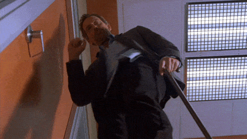 a man in a suit is standing in front of a door with a sign that says ' emergency exit ' on it