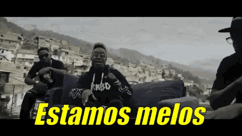 a group of men sitting on a couch with the words " estamos melos " in yellow