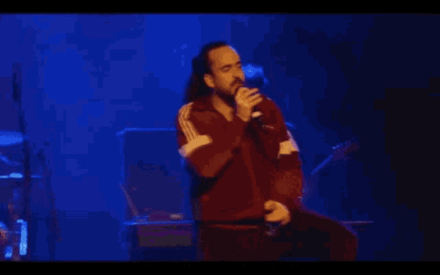 a man singing into a microphone with the words " you 're putting people in danger " behind him