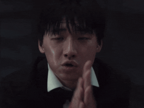 a close up of a man with his hands folded in prayer