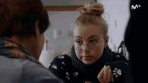a woman wearing glasses and a black sweater with paw prints looks at another woman