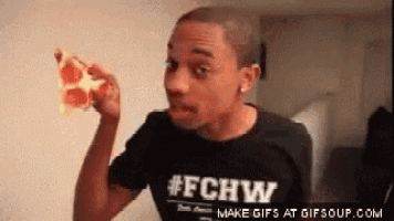a man in a # fchw shirt is eating a slice of pizza