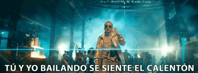 a man is dancing in front of a crowd with the words " tu y yo bailando se siente el calenton " above him