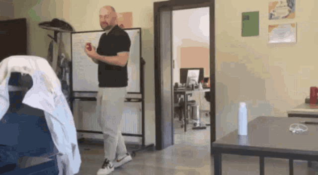a man is standing in a room holding an apple in his hand