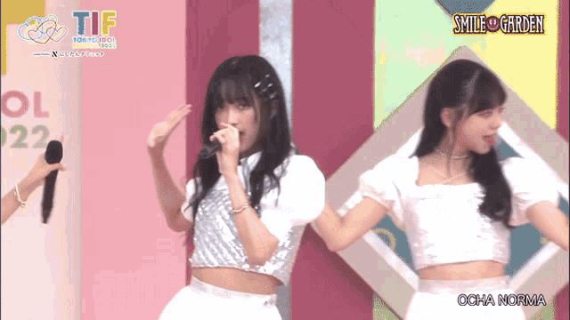a girl singing into a microphone next to another girl with smile garden written on the bottom