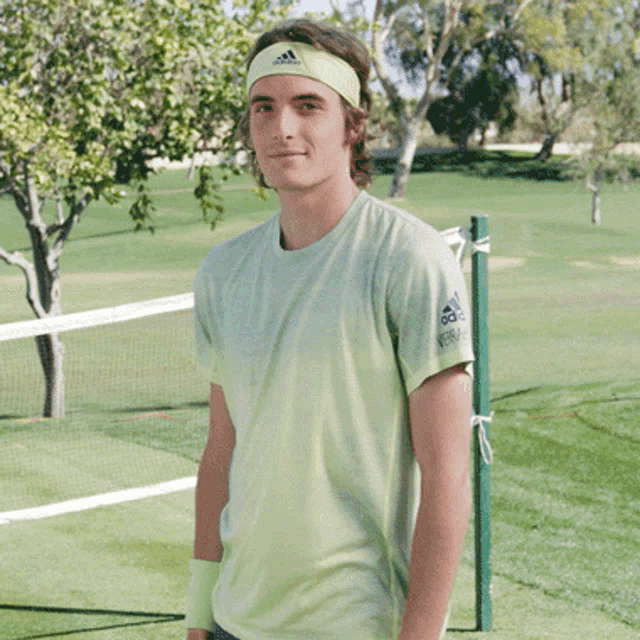 a young man wearing an adidas headband and a green shirt