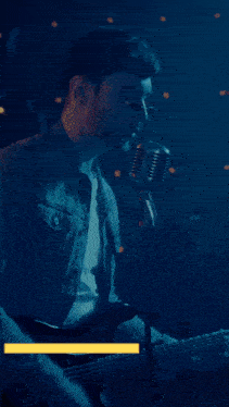 a man sings into a microphone while playing a guitar