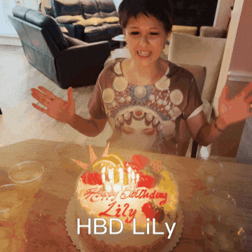 a woman blows out candles on a birthday cake that says hbd lily