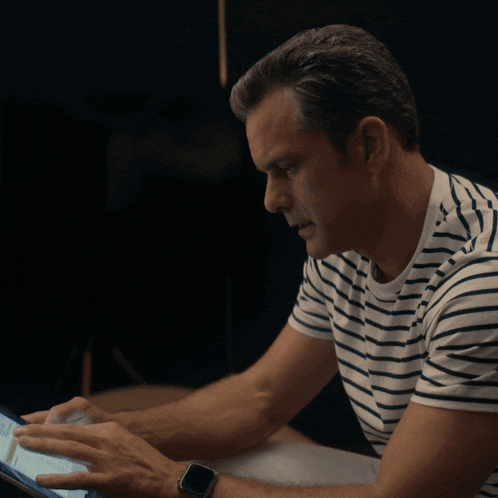 a man in a striped shirt looks at a tablet