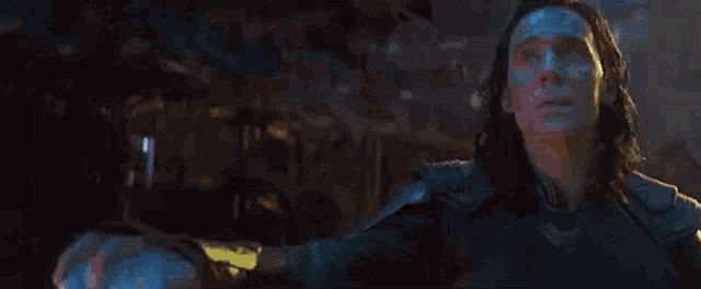 loki is holding a blue cube in his hands .