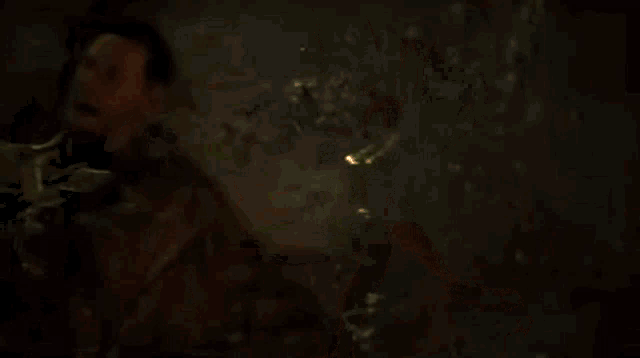 a monster is crawling on a man 's head in a dark room