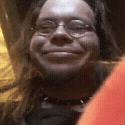 a woman wearing glasses and a choker is smiling for the camera