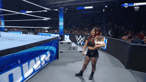 a woman in a wrestling ring holding a wrestling championship