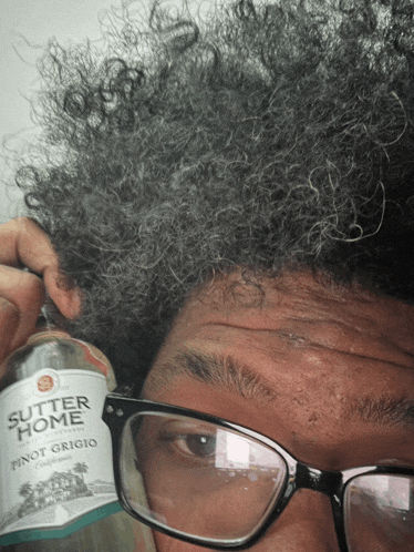 a man holds a bottle of butter home pinot grigio in front of his face