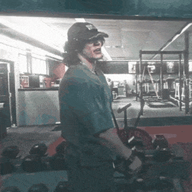 a man wearing a kentucky hat is lifting a barbell in a gym