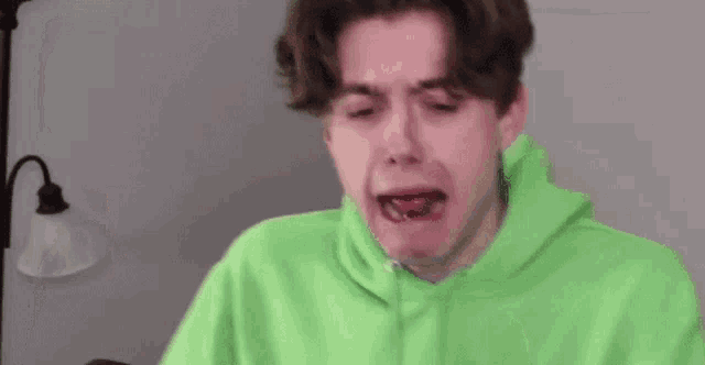 a young man wearing a neon green hoodie is making a funny face .