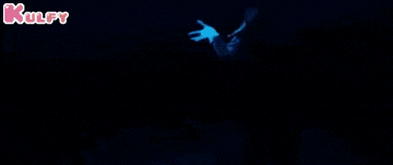 a person is holding a full moon in their hands in the dark .