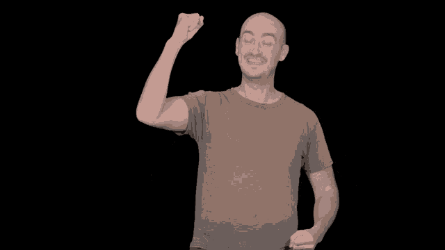 a man in a grey t-shirt is raising his fist in the air