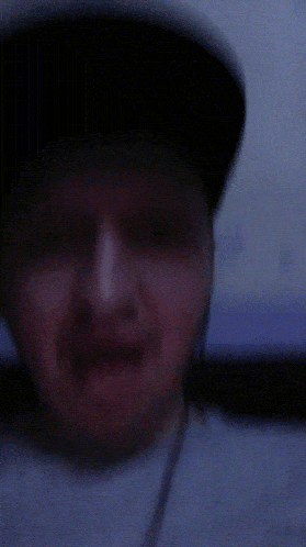 a man wearing a hat and a gray shirt is smiling