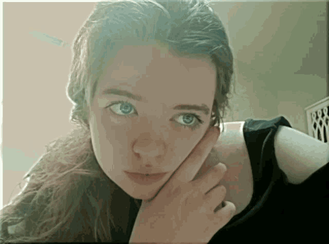 a woman with long hair and blue eyes looks at the camera