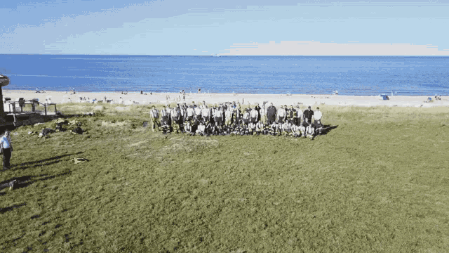 a large group of people are posing for a picture on the beach