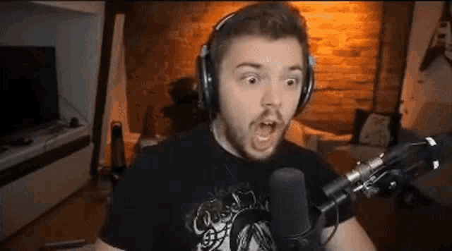 a man wearing headphones is screaming into a microphone in a living room .