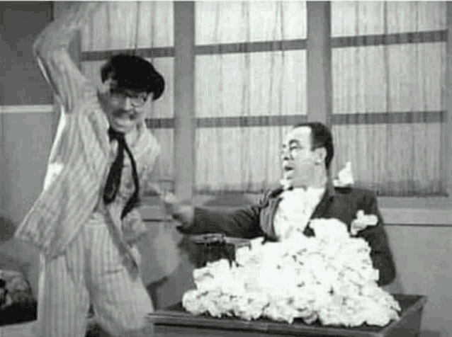 a man in a suit is standing next to a pile of paper towels .