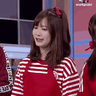 a girl wearing a red apron and a striped shirt is standing next to another girl .
