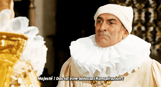 a man in a white hat and collar says majeste das ist eine kolossal konspirazion