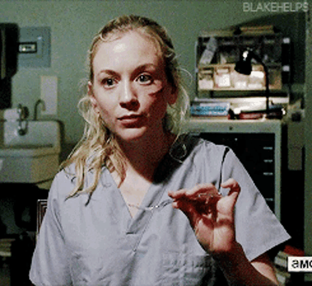 a woman in a scrub top holds a syringe in her hand with blakehelps written on the bottom