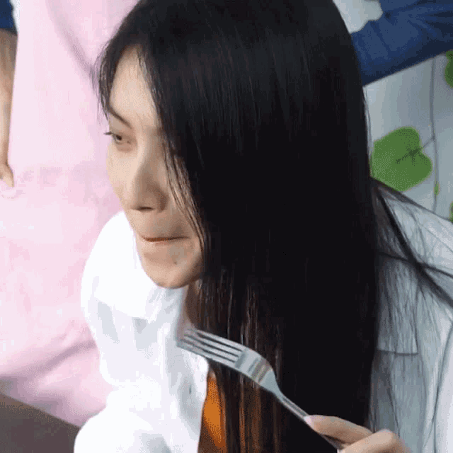 a woman with long black hair holds a fork in her hand