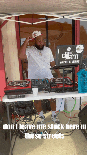 a man standing behind a table with a laptop that says djlam