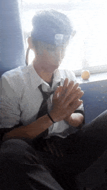 a man in a white shirt and tie is sitting in front of a window with his hands together